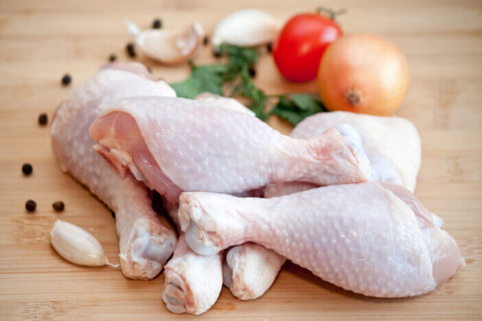 Raw chicken legs with vegetables and spices on the chopping board