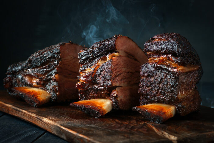 A large steaming fragrant piece of baked beef brisket on the ribs with a dark crust. Classic Texas barbecue