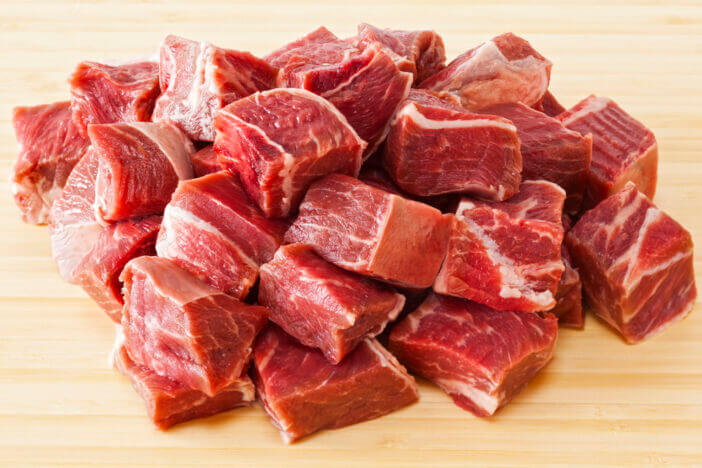 Beef Stew Meat Raw - diced raw blade or chuck steak, on white background.