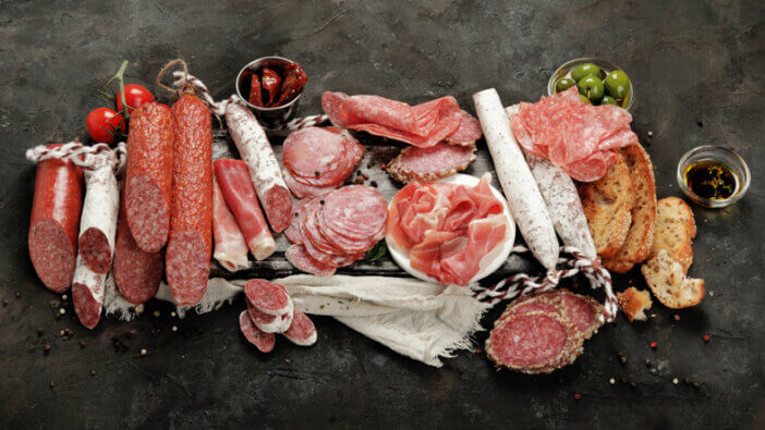 Sasusages assortment on dark background. Meat product made of finely chopped and seasoned meat.