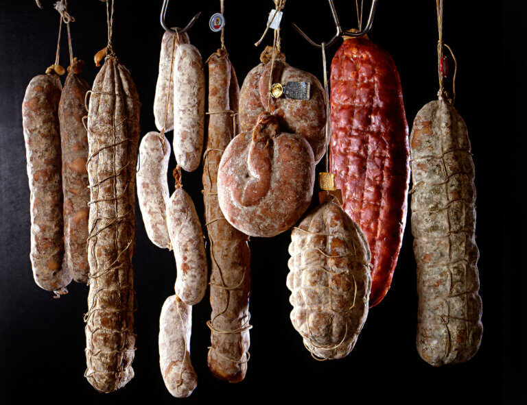 Row of different flavoured and shaped hanging salamis, traditionally made from savoury pork and beef hung out to dry and cure