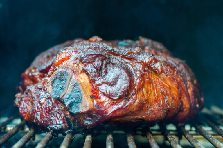 Pork shoulder on a smoker grill getting cooked for pulled pork.