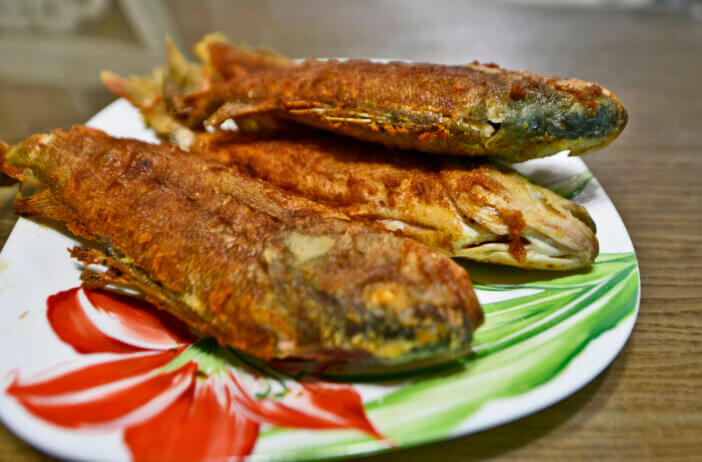 Country-style fried river perch in a frying pan.