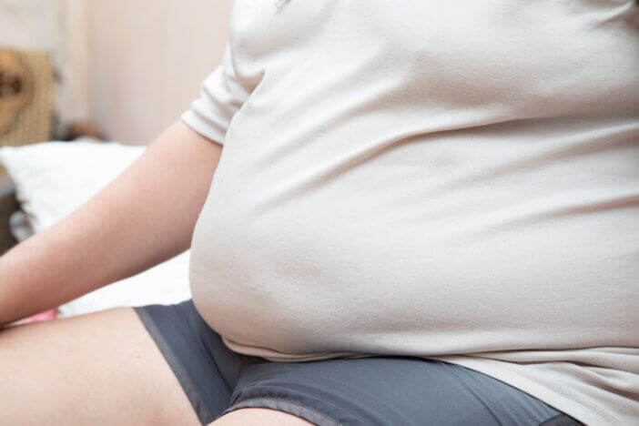 A man with a big belly is sitting on the bed.