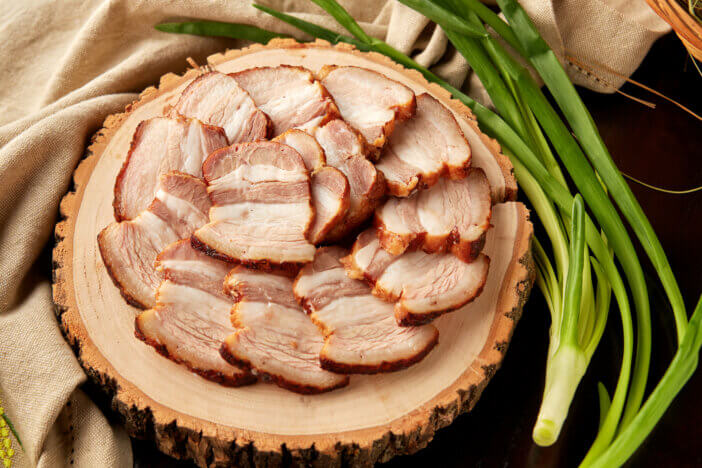 Delicious roasted pork belly sliced on wooden plate, served with green onion