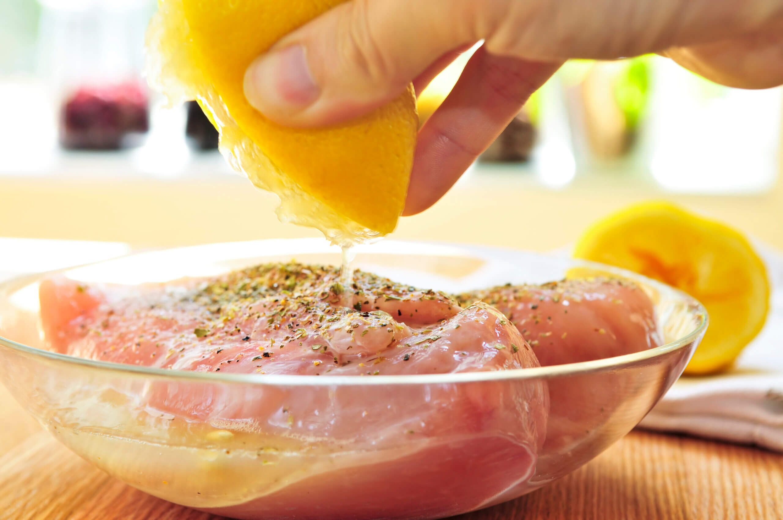 Marinating raw chicken breasts in lemon juice and herbs