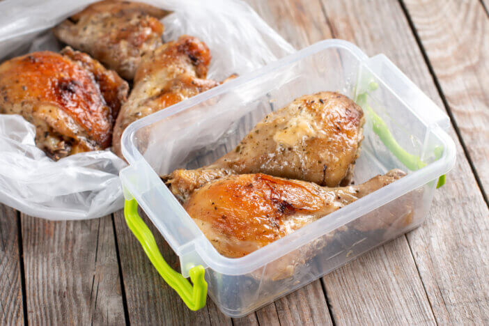 Baked chicken legs in a container. Ready meals. Frozen food