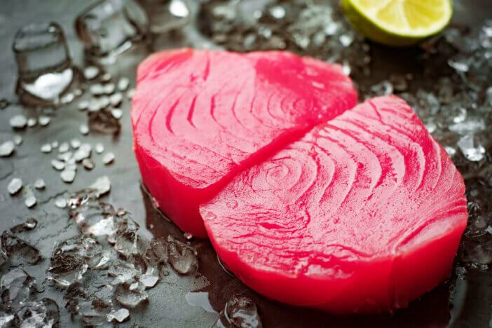 Sliced fillets of tuna on a stone background with salt and ice