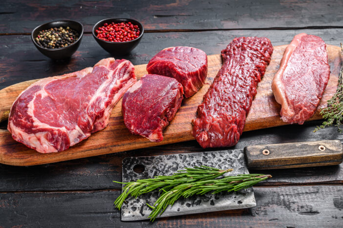 Raw prime black angus beef steaks fillet Mignon, rib eye or cowboy, Striploin or new york, skirt or machete. Wooden dark background. Top view.