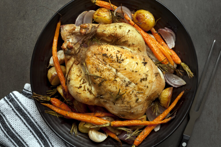 Roasted chicken dinner with vegetables and herbs.  Overhead view.