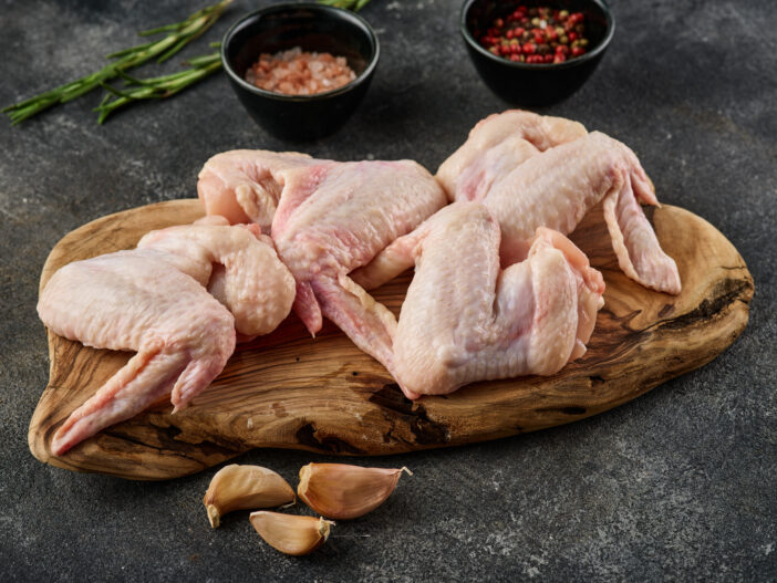 Raw chicken wings Poultry meat with spices, salt and pepper, on gray background. Close up.