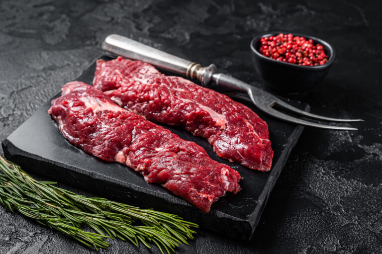 Raw Machete steak or hanging tender cut with herbs. Black background. Top view.