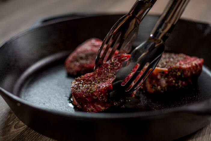 Chef is placing tenderloin steaks with kitchen tongs