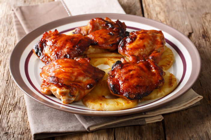 Huli-huli chicken is a grilled chicken dish in Hawaiian cuisine, prepared by barbecuing closeup on a plate. Horizontal