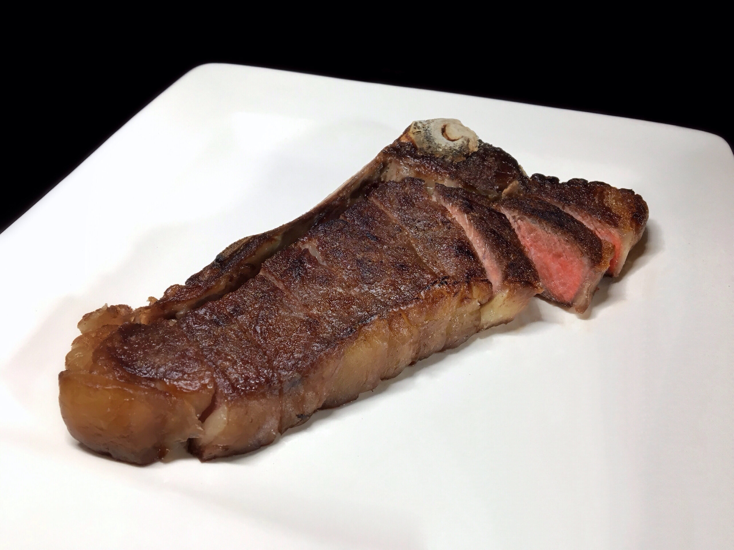 Reverse seared New York strip steak - medium rare - portioned off the bone, to serve