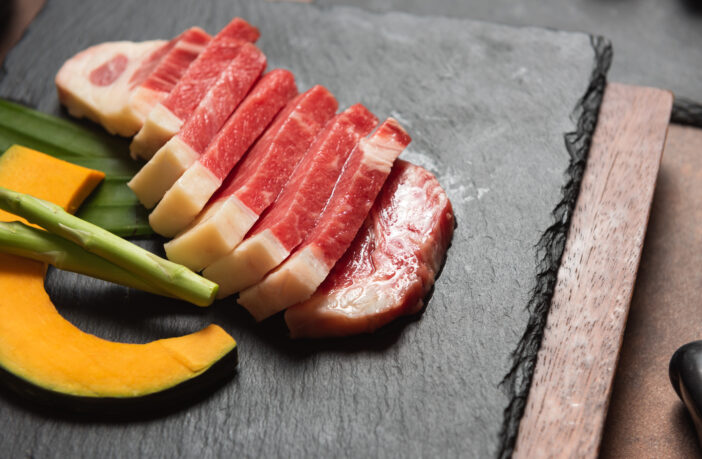 Fresh raw beef brisket slice with pumpkin and asparagus on the black marble dish rock. healthy and raw food concept.