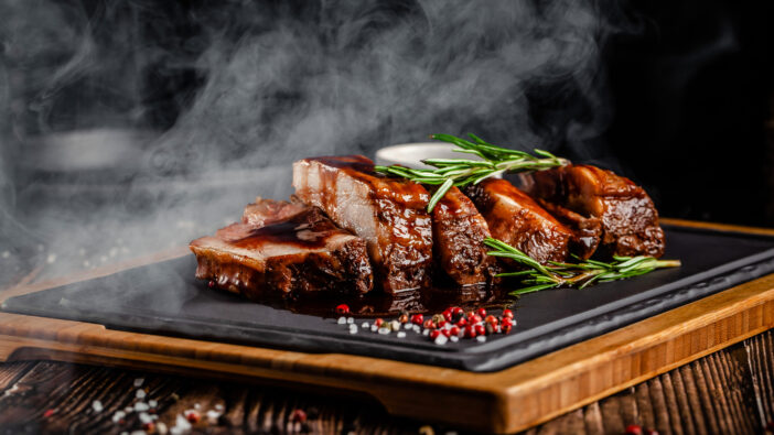American food concept. Grilled pork ribs with grilled sauce, with smoke, spices and rosemary. Background image. copy space