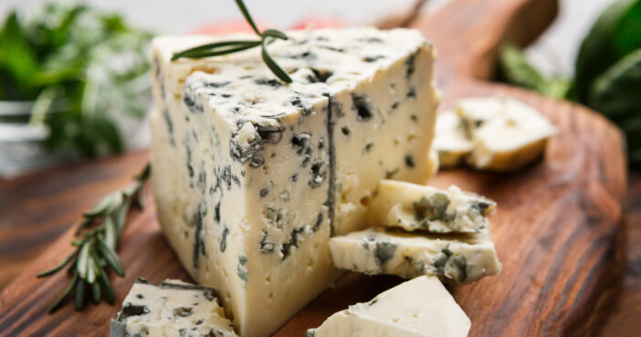 Blue cheese and rosemary sprigs on wooden cutting board