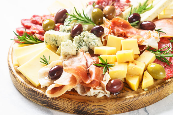 Antipasto platter. Cheese and meat - jamon, salami, olives at wooden serving board.