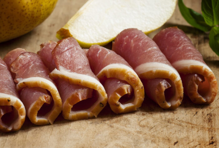 Pear and Italian ham on a board, selective focus