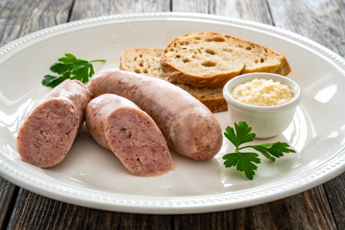 Easter breakfast - boiled white sausages, toasts and horseradish on wooden table