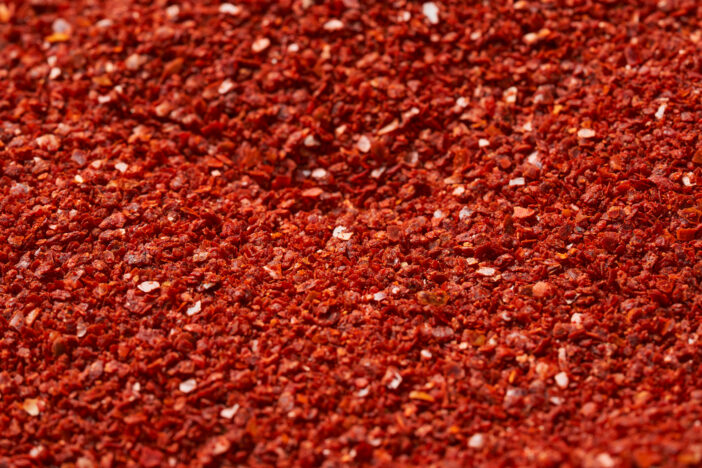 close up dry red pepper flake powder coarse. Korean chili ground Gochugaru texture background. Korean red pepper flake powder coarse ground gochugaru.