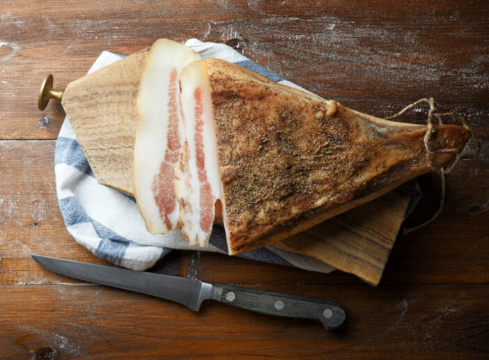 Sliced bacon on old table, flat lay.