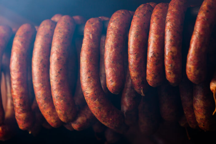 Traditional food. Smoked sausages meat hanging in domestic smokehouse.