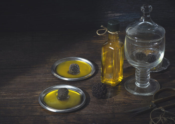 Truffle  oil on a rustic wooden table, how to preserve the aroma and taste of black truffle. Preserving black truffle. Atmospheric still life in the style of a chef's table,  front view, copy space