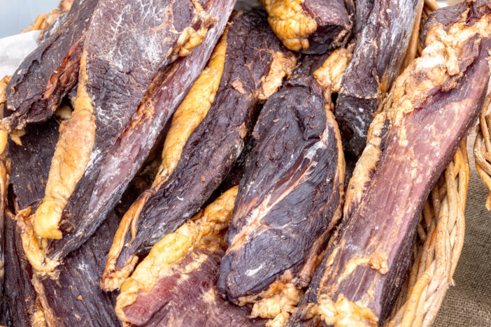 Close-up pieces of homemade beef jerky in basket at farmers market top view.