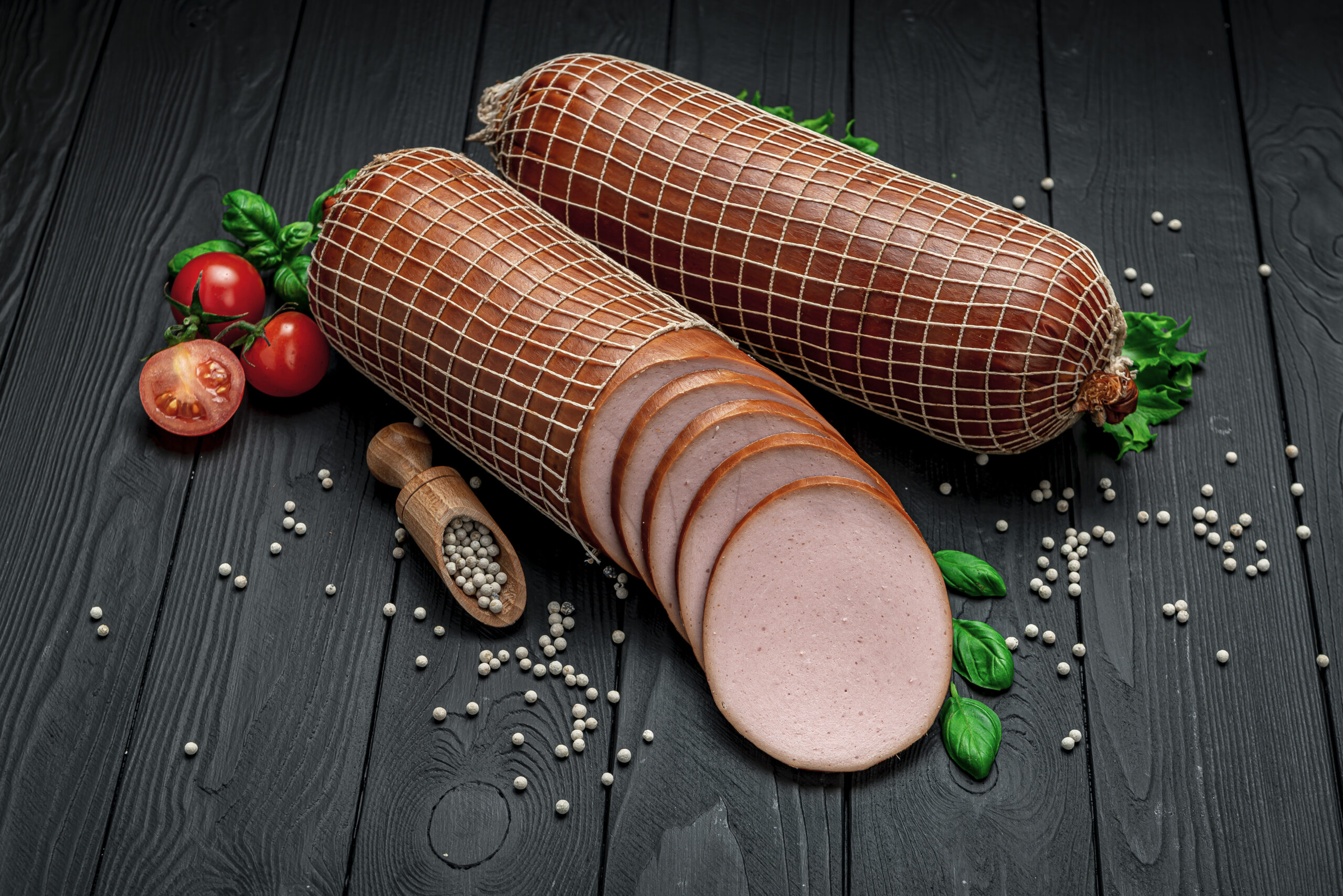 Italian thick boiled sausage on a dark background. From different types of meat. Photo for the menu. Advertising.