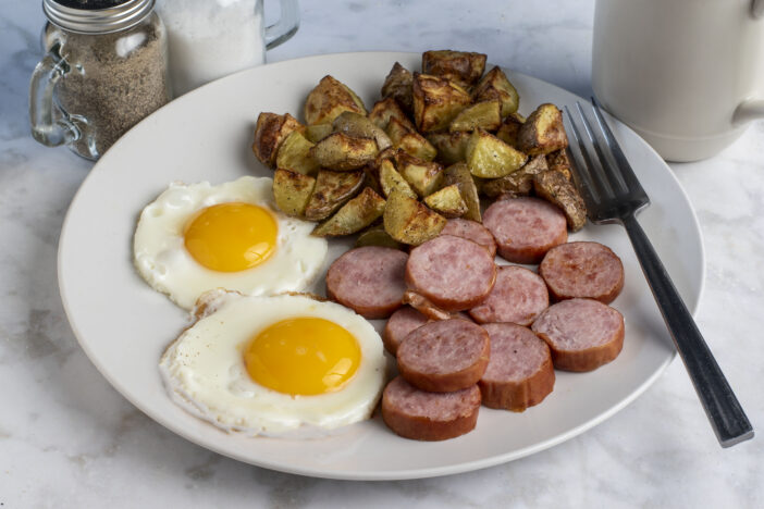 breakfast plate consisting of  fried eggs  and kielbasa served with home fries