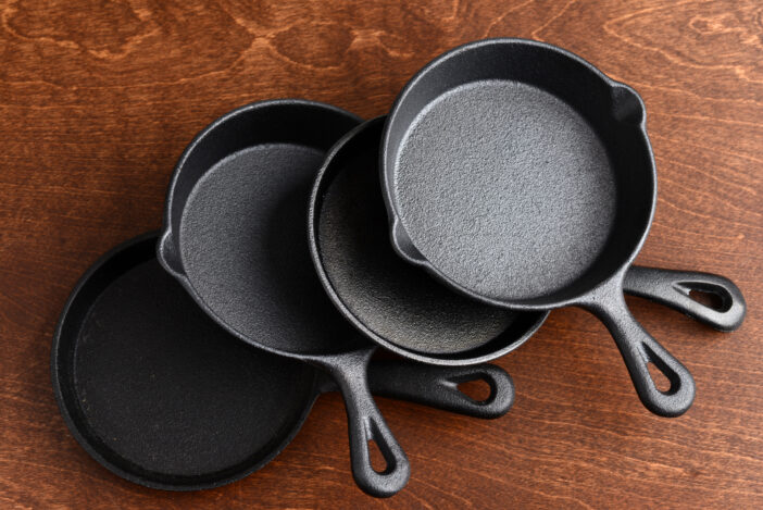 pile of cast iron skillets on wood table top view