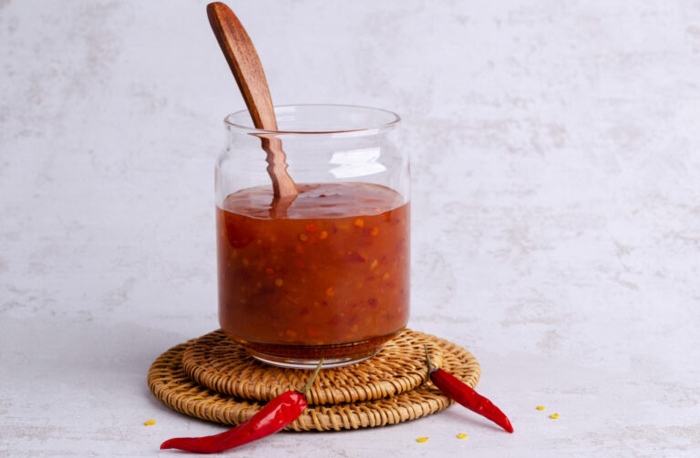 Traditional chili sauce in a glass on a light background. Selective focus. Copy space.