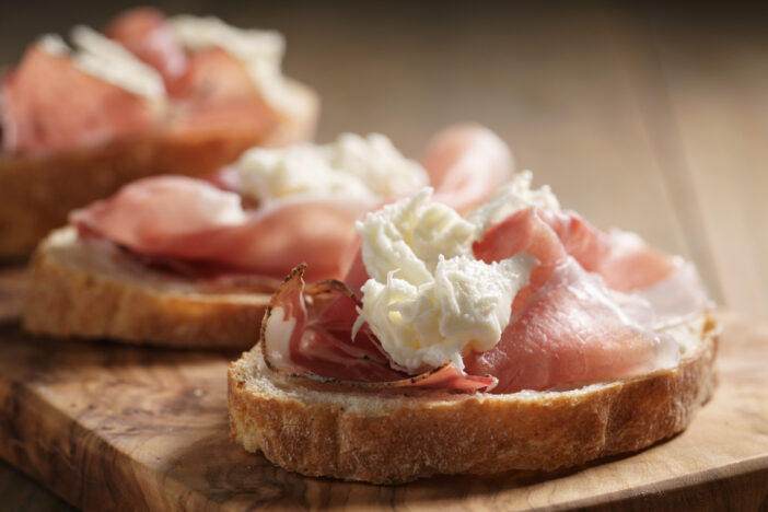 simple ciabatta slices with speck and mozzarella on wood table