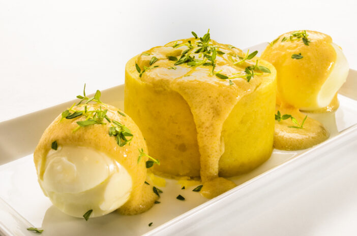 hard boiled eggs with mustard sauce, mashed potatoes and fresh thyme on a white plate