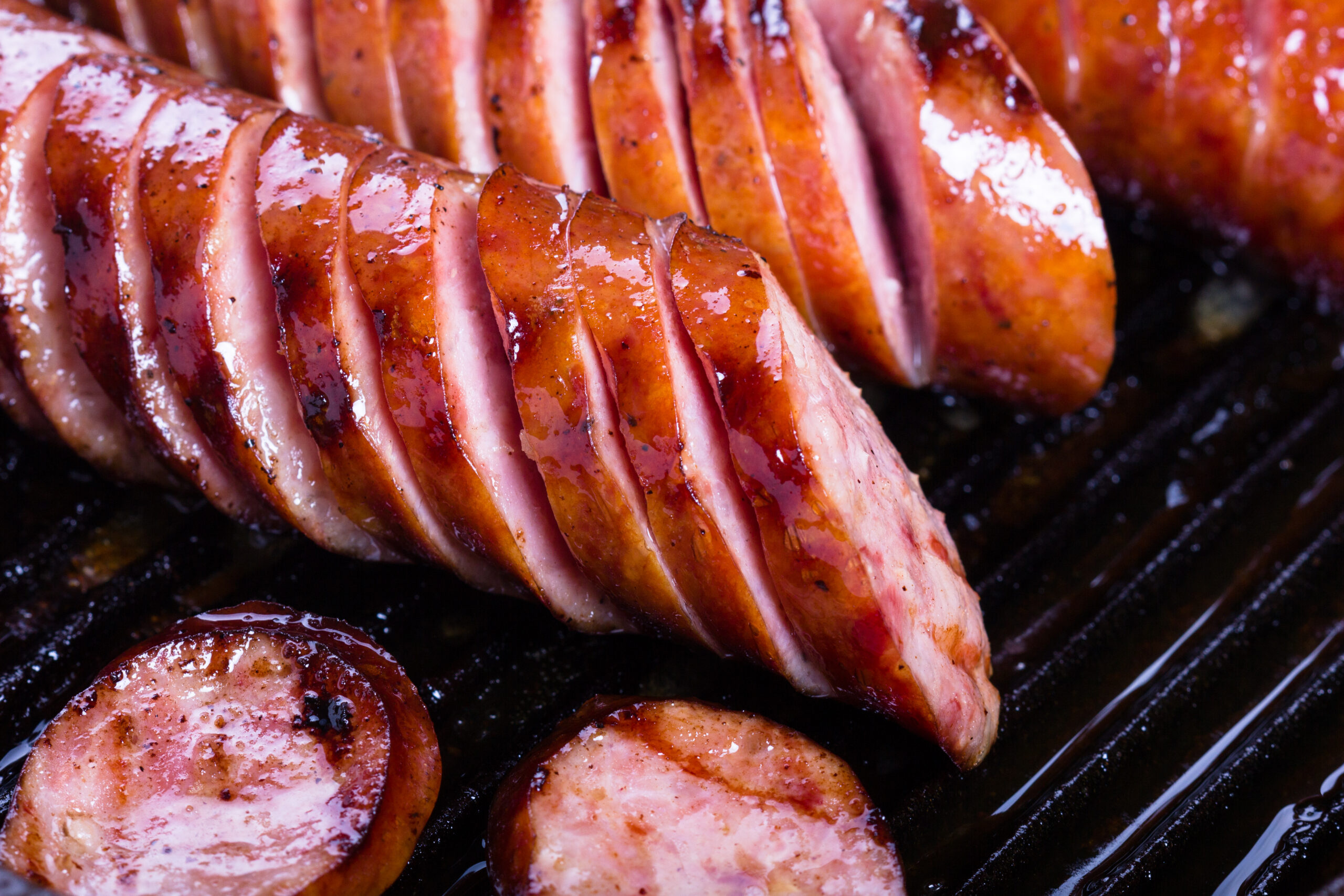 Polish traditional sausages fried on a cast iron skillet.