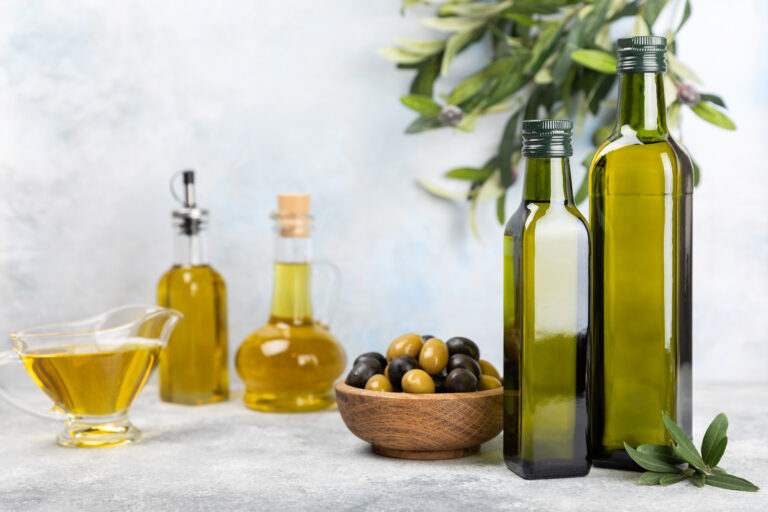 Olive oil in a bottle on a white texture background. Oil bottle with branches and fruits of olives. Place for text. copy space. cooking oil and salad dressing.