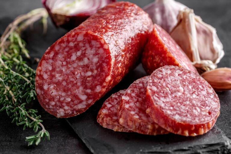 Traditional smoked salami sausage with spices.Salami sausage slices on a black chopping Board. Dark background.