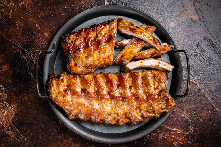 BBQ pork spare ribs St Louis with hot honey marinade in a steel tray. Dark background. Top view.