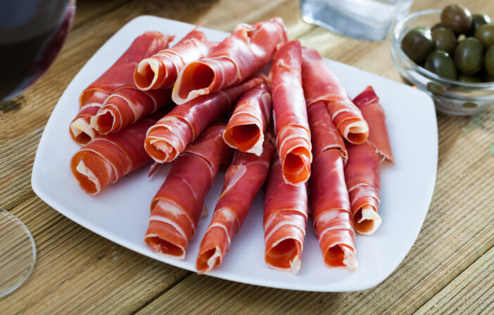 Traditional Spanish meal - rolls of iberian jamon served at plate, nobody