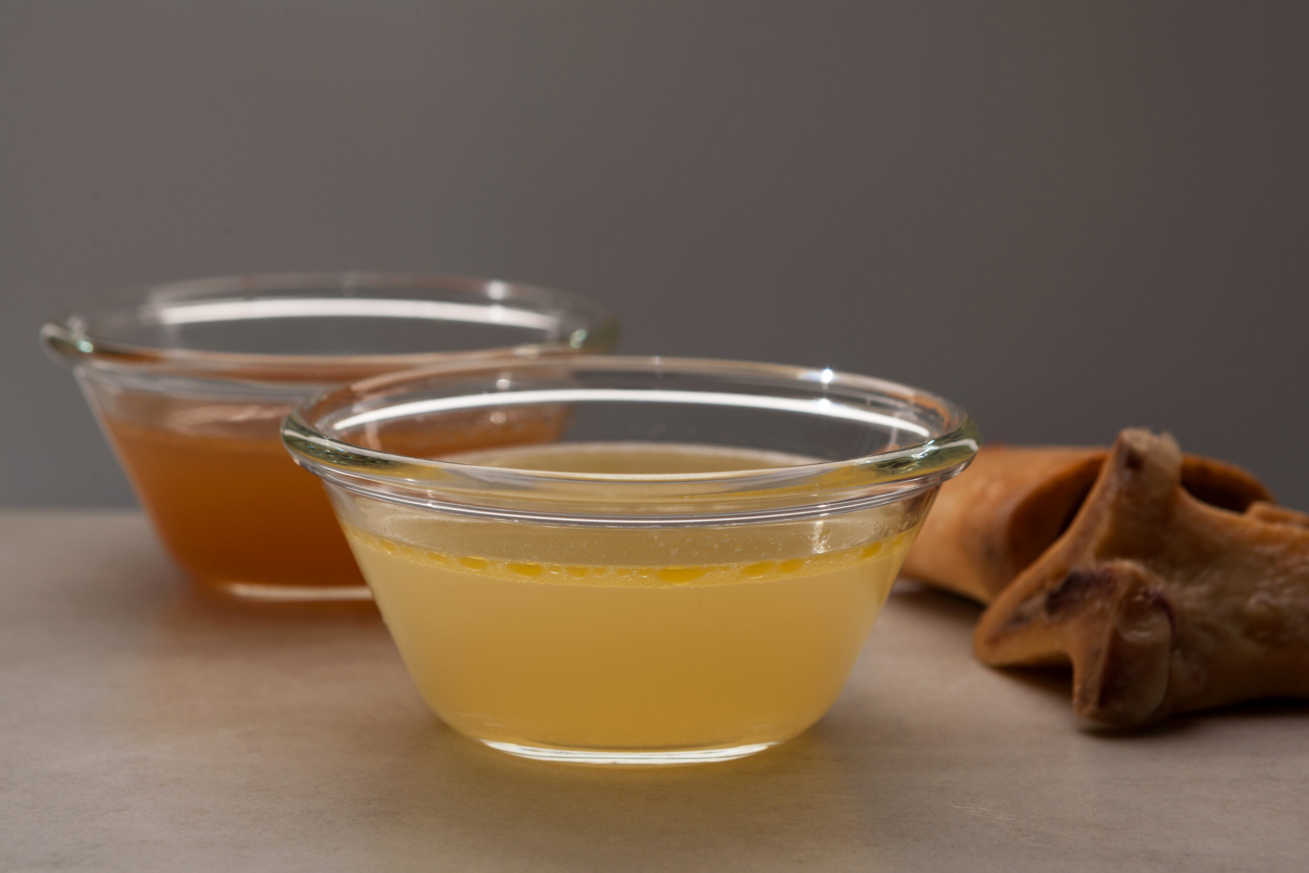 Two types of bone broth in glass bowls. Close-up, selective focus. Beef bones are source of natural collagen, which is useful for joints and provides the body with essential amino acids.