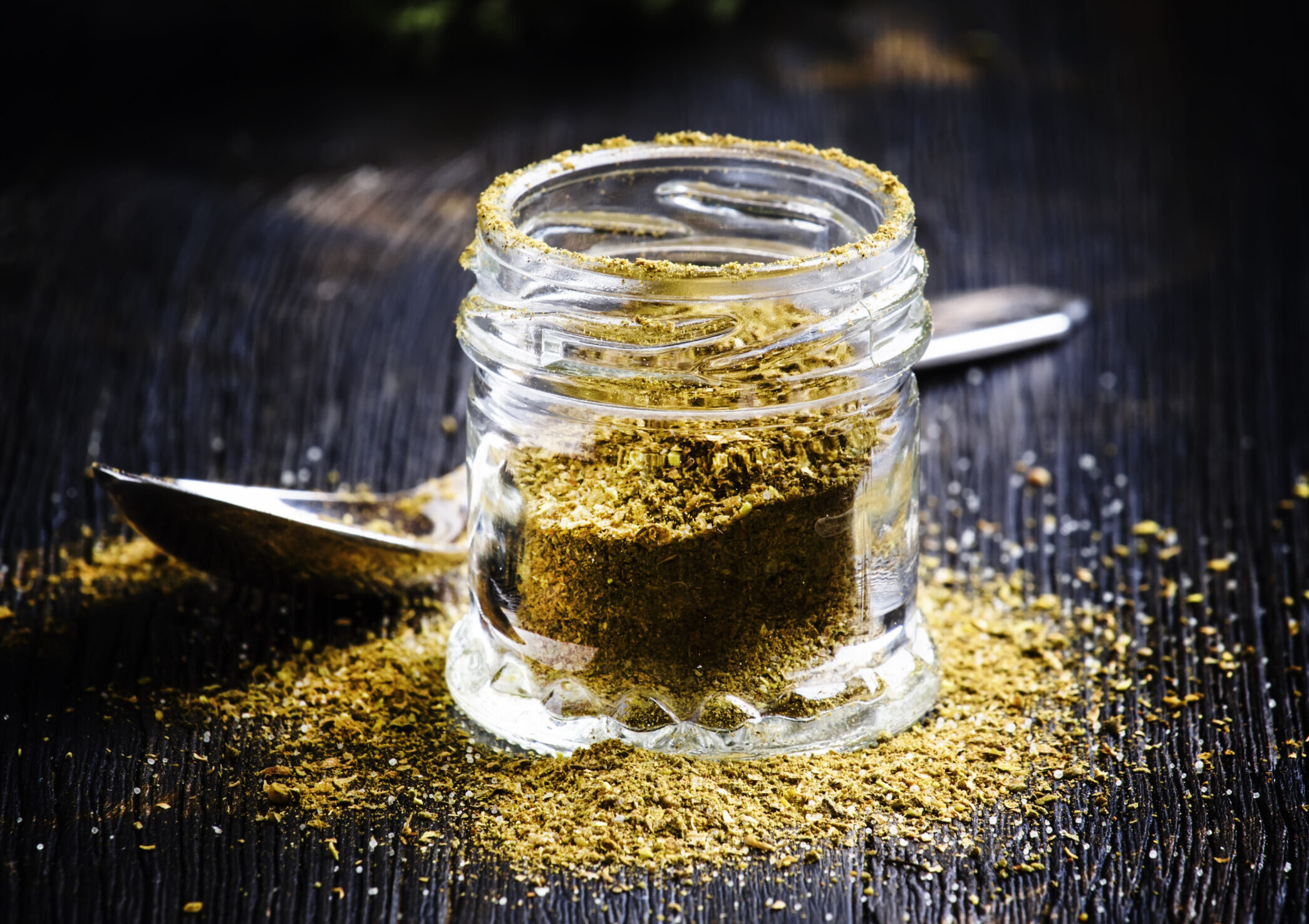 Traditional Caucasian seasoning with herbs and spices, khmeli suneli in a glass jar, black background, selective focus