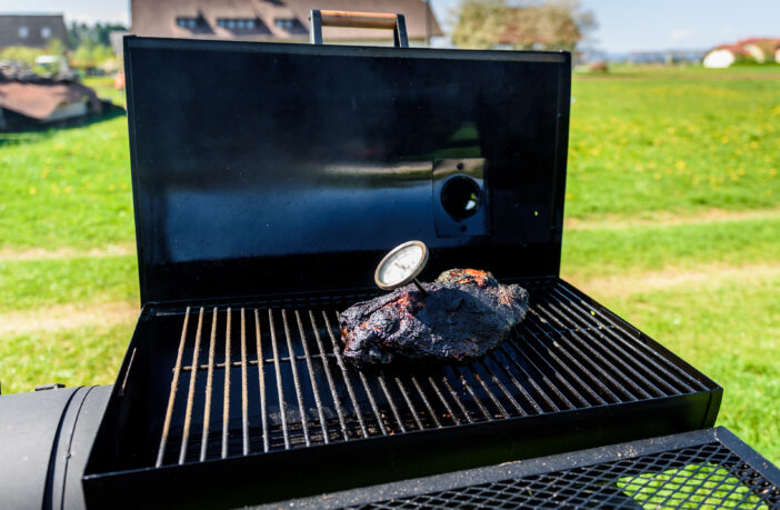 family backyard barbecue - BBQ picnic. Checking the correct temperature with meat thermometer.