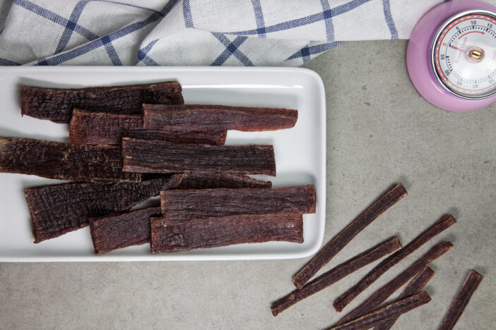 Sliced of Homemade Beef Jerky in crockery plate with napkin and timer on table