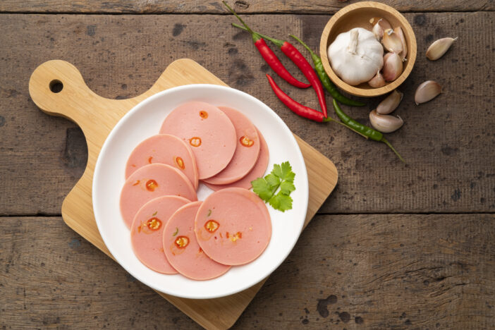 Spicy Sliced Bologna sausage with Chili in white plate.Top view