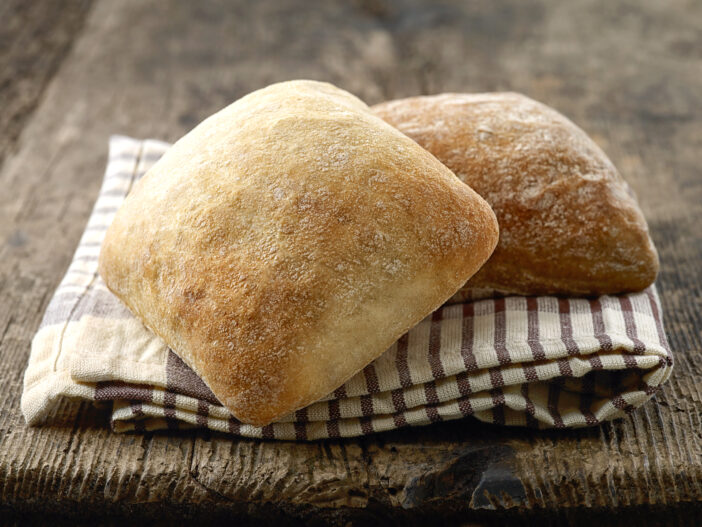 two ciabatta bread buns on wooden table