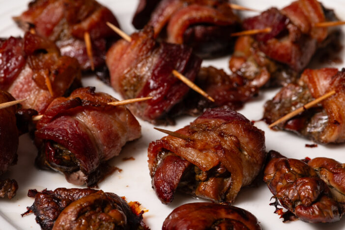 Cooked chicken liver wrapped with bacon. Roasted liver kebabs with on a white plate.