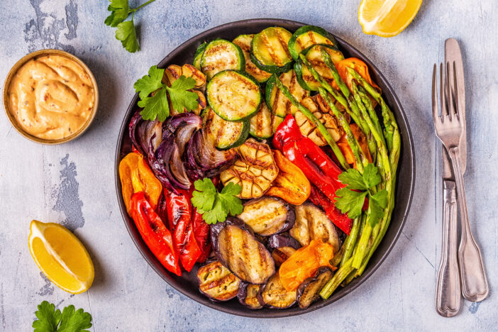 Grilled vegetables on a plate with sauce, top view.