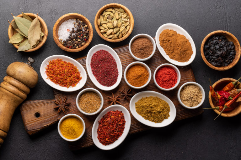 Various dried spices in small bowls on wooden board